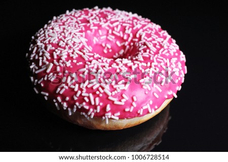 Donut. Beautiful pink donut on black reflective studio background. Isolated black shiny mirror mirrored background for every concept.