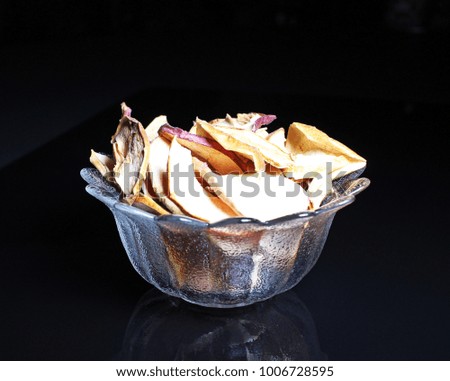 Apple slices. Dry dried apple chips on black reflective studio background. Isolated black shiny mirror mirrored background for every concept.