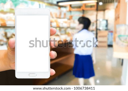 Girl use mobile phone, blur image of inside the bakery shop as background