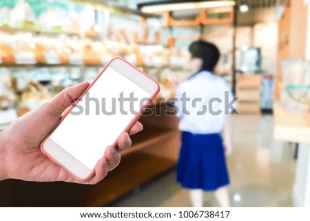 Girl use mobile phone, blur image of inside the bakery shop as background