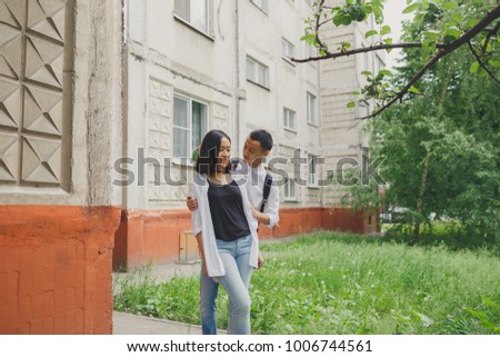 young Asian couple walks in the city Park. emotional portrait of students. young girl and guy brunette having fun on Valentine's day. concept: 14 February