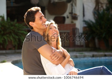 Close up portrait of smiling handsome couple sitting together outside by pool