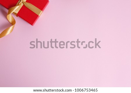 red gift with a gold ribbon on a pink background, background to the day of St. Valentine and the eighth of March, international women's day