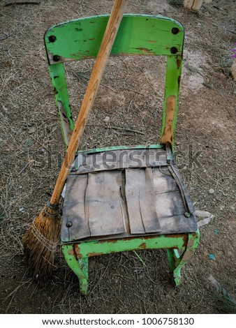 Weathered old rustic green chair with broom