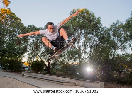 young American man practicing radical skate board jumping and enjoying tricks jumps and stunts in concrete half pipe skating track in sport and healthy lifestyle concept
