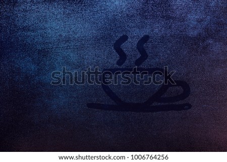 Cup of hot drink symbol draw on frozen window concept background. Cup of hot coffee or tea on wet glass window