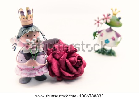 Antique decorcation of Angel doll holding flowers near dry red rose and frog with crowd isolated on white background with copy space for text. Valentine holiday day.