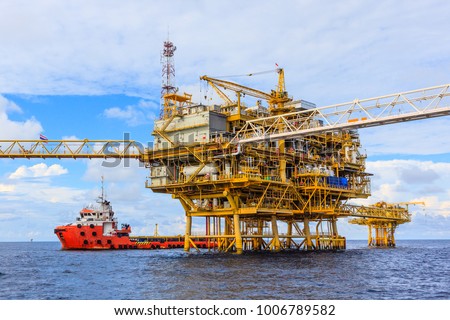 Offshore oil and Gas central processing platform and remote platform produced oil, natural gas and liquid condensate for set to onshore refinery from offshore in ocean sea and along with supply boat. Royalty-Free Stock Photo #1006789582