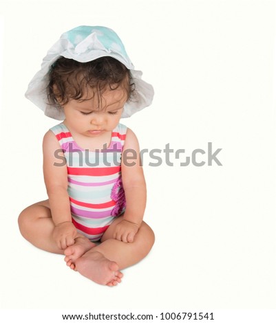 Cute baby girl in hat and striped swimsuit, isolated on white background
