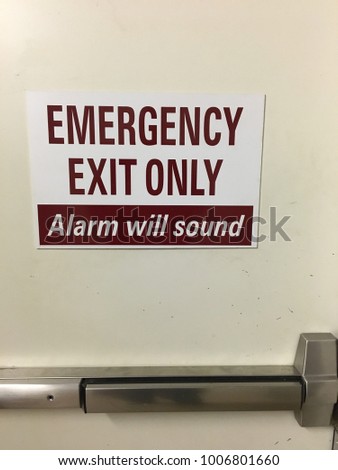 A sign for an emergency exit warns users that an alarm will sound if it is opened for non-emergencies 