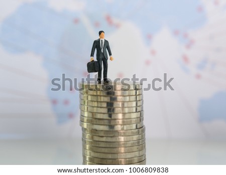 Business logistics concept,miniature business people stand on silver coins with world map  background