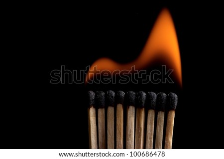 Burning matchstick on black background