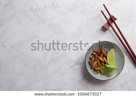Fried insects (wood worm insect) crispy served with chopsticks and lime, selective focus