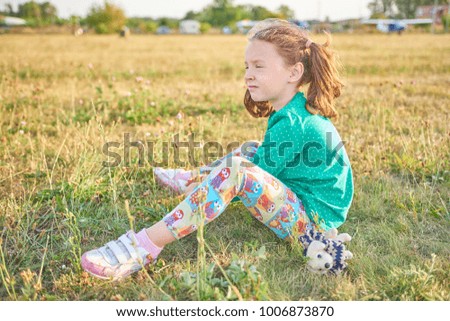 Little girl is playing while sitting on green meadow