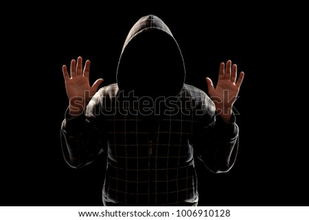 Silhouette of a man in a hood on a black background, the face is not visible, shows the palms in the camera. The concept of a criminal, incognito, mystery, secrecy, anonymity.