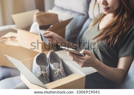 young woman received online shopping parcel opening boxes and buying fashion items by using credit card, Shop online and delivery concept Royalty-Free Stock Photo #1006919041