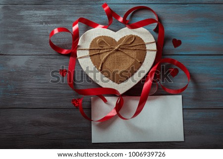 Gift box in the shape of a heart and a white envelope on a blue wooden background
