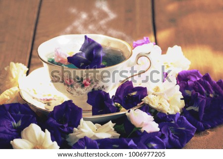 Still life image of organic fresh flower tea.Afternoon tea from white rose and pea flower mixed up with properly degree of hot water.Healthy cup serve in white sweet porcelain.Vintage color tone.
