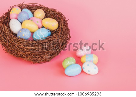 Colorful easter eggs in nest on pink pastel color background with space.