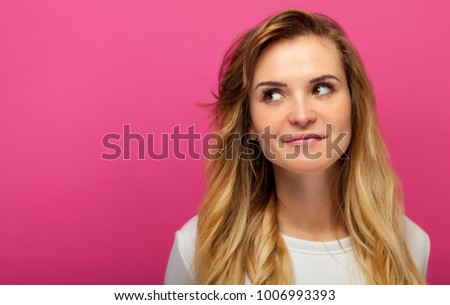 Portrait of beautiful girl on pink background looking at something, copy space Royalty-Free Stock Photo #1006993393