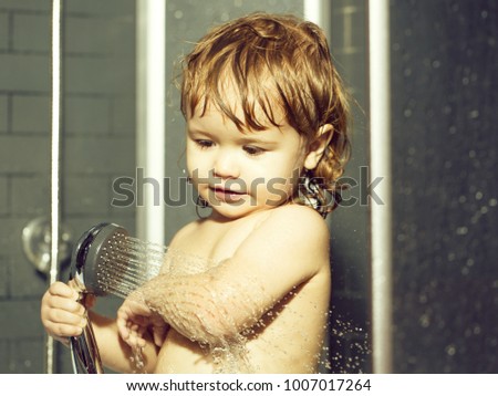 Cute happy smiling funny undressed boy child with blonde curly wet hair taking shower in bath with water indoor, horizontal picture