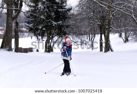 A little girl practicing skiing againts a beautiful winter landscape 