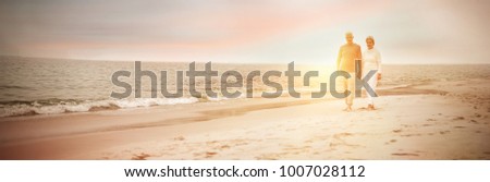 Senior couple walking on the beach on a sunny day Royalty-Free Stock Photo #1007028112