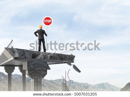 Rear view of engineer in helmet holding stop sign while standing on broken bridge with skyscape and nature view on background. 3D rendering.