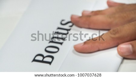 Company bonus concept - close up blurred and defocused annual bonus with boss hand