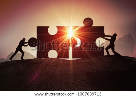 Teamwork, partnership and cooperation concept. Silhouettes of two businessman joining two pieces of puzzle together. Royalty-Free Stock Photo #1007039713