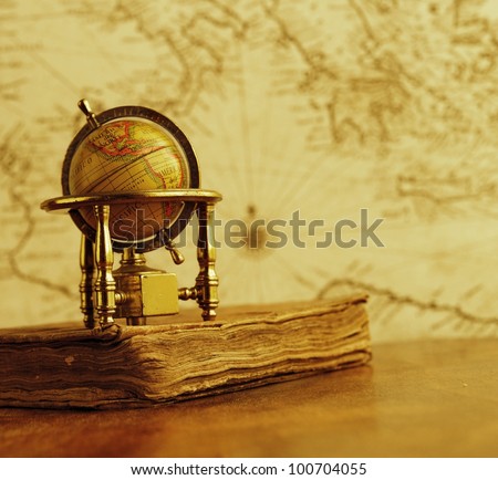 Globe and vintage book against map on a wall.