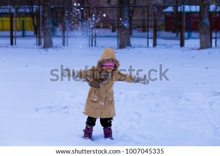 A cute little girl covered with snow has fun in winter park, wintertime