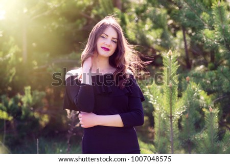model in black dress. In the warm sunny park. beautiful portrait Hand on the neck