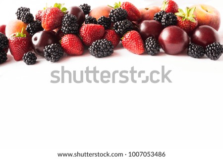 Black and red food. Ripe blackberries, strawberries, plums and peaches on white background. Berries at border of image with copy space for text. Background berries. Various fresh summer berries. 