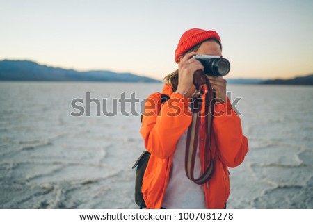 Professional female photographer taking picture of wild environment of national park in USA with desolate arid surface, young woman tourist take picture on digital camera during travel in Death Valley