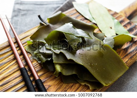 Soaked kelp on wooden board with chopsticks, kombu seaweed. Traditional asian, japanese and korean food. Raw, vegan and vegetarian food concept. Royalty-Free Stock Photo #1007092768