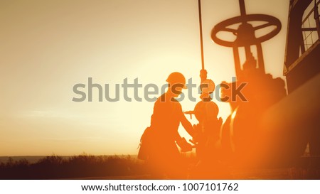 Oil worker is checking the oil pump on the sunset background. Royalty-Free Stock Photo #1007101762