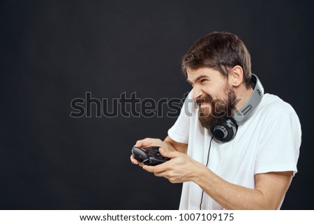 man plays a joystick in the console on his neck headphones on a black background                               