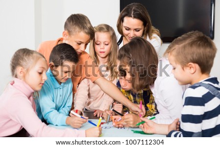 Professor and elementary age caucasian children drawing together one picture