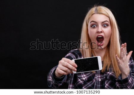A girl, is holding a smartphone and is frustrated with shouts. On a black background.
