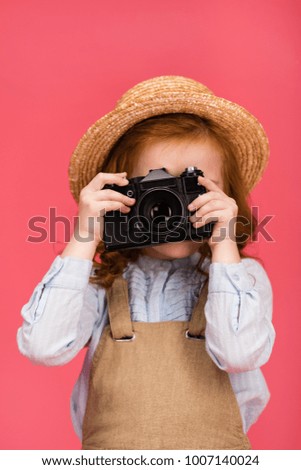 obscured view of child holding photo camera isolated on pink