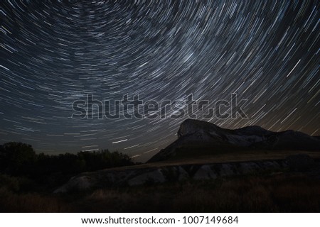 Beautiful star trails time-lapse over the hills. Polar Star at the center of rotation. Lateral light from the full moon on the chalk hills. 