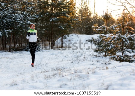 Picture of cheerful sportswoman in sneakers on morning run in winter forest