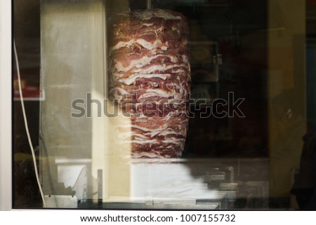 Photo of meat for shaurma cooking behind glass