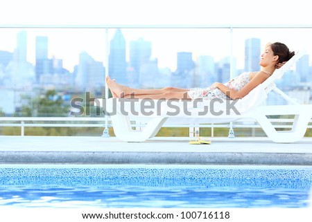 Urban luxury city lifestyle woman lying by pool relaxing in sun lounger during summer in Montreal, Quebec, Canada.