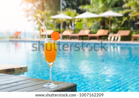 Orange juice with carrot slice in cocktail glass on wooden table at outdoor swimming pool, summer tropical holiday concept Royalty-Free Stock Photo #1007162209