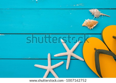 Summer concept background : Sandals sea shell and starfish on blue rustic wood background.