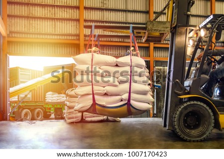 Forklift handling white sugar bags for stuffing into containers outside a warehouse. Distribution, Logistics Import Export, Warehouse operation, Trading, Shipment, Delivery concept. Royalty-Free Stock Photo #1007170423
