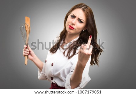 Beautiful chef woman making horn gesture on grey background