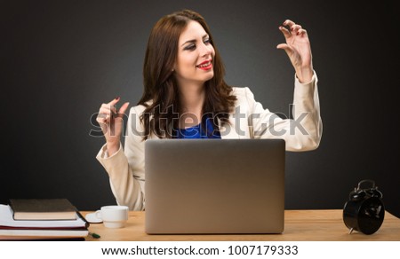 Business woman working with her laptop and making tiny sign on black background